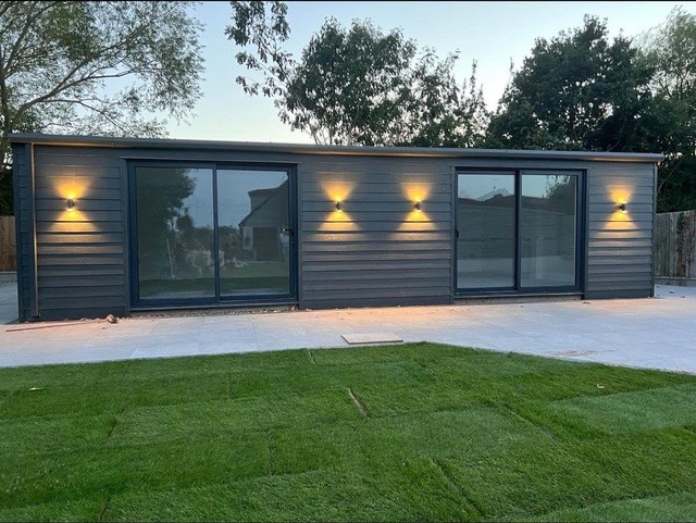 Dark-clad build with wall lights at dusk
