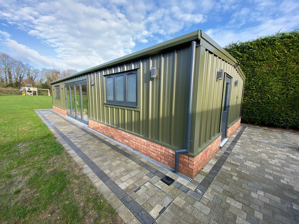 Green-clad build with glazed doors on a brick plinth